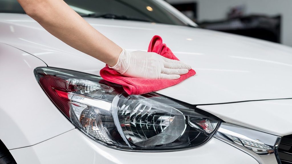 Professionnel du nettoyage de voiture enlevant avec précaution la sève avec de l'alcool à friction.