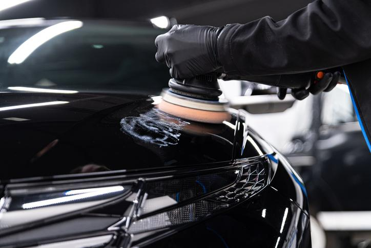 Étudiant suivant une formation en esthétique automobile qui polit carrosserie d’auto.