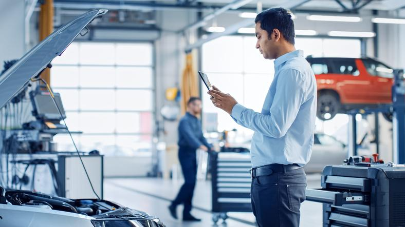 Diplômé d’une formation en mécanique automobile regardant un horodateur sur tablette.