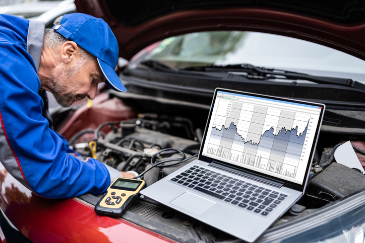 Étudiant en formation mécanique automobile qui utilise un appareil de diagnostic électronique.