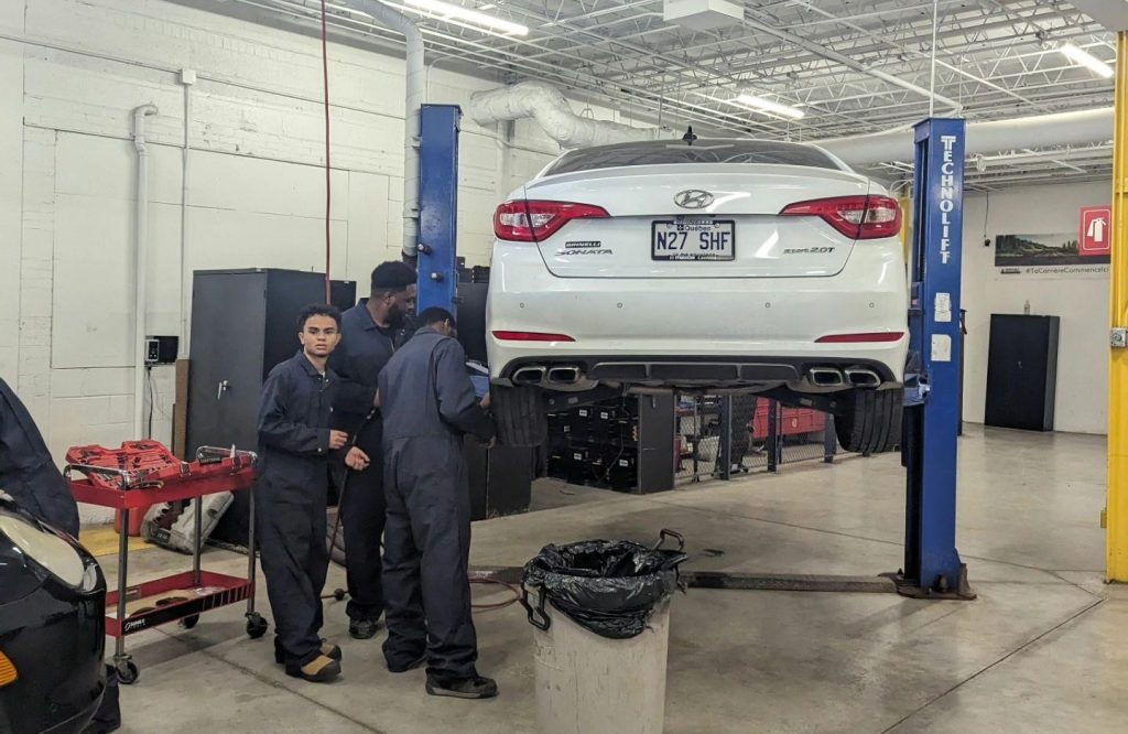 Étudiants en école mécanique Montréal qui réparent un véhicule.