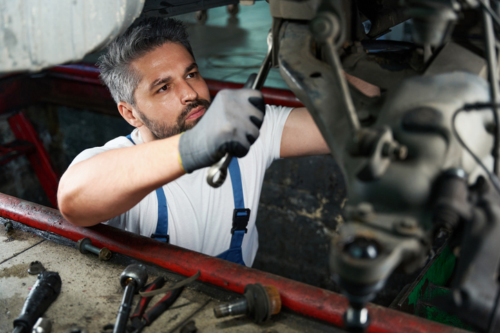 Technicien automobile travaillant dans un garage après un DEP en Mécanique automobile