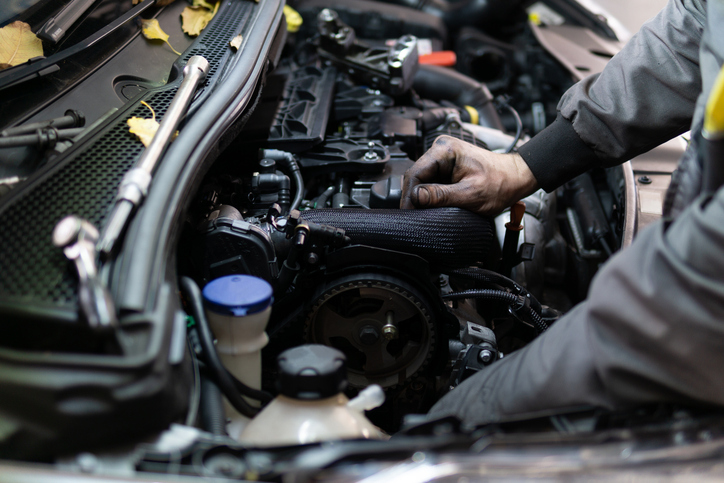 étudiant en formation mécanique observant une fuite sous une voiture