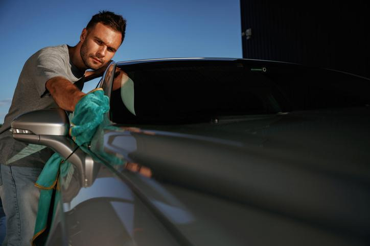 étudiant en formation esthétique automobile appliquant une protection sur une carrosserie