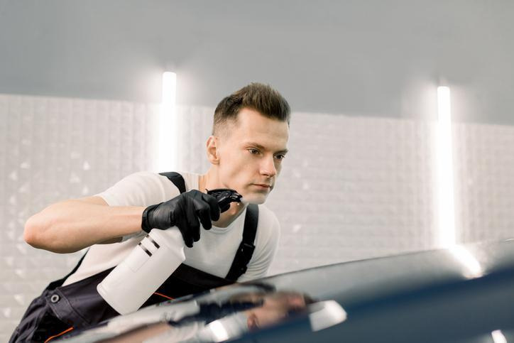 technicien en esthétique automobile nettoyant un véhicule pendant l'été